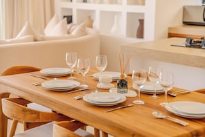 Une table à manger dressée avec des assiettes, des verres et des couverts, agrémentée d’une bougie décorative et d’un diffuseur de parfum à bâtonnets au centre.