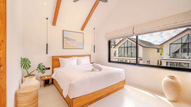 Un dormitorio moderno con una cama de madera, un ventanal y vistas a edificios.