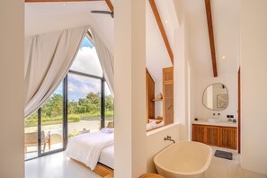 Une chambre avec une grande fenêtre, un lit et une vue sur la verdure.