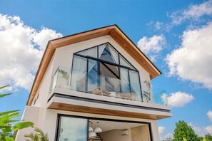A modern two-story building with a balcony, large windows, and a wooden facade. - Aintrazy Villa by Betterplace (Unggasan)