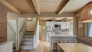 Uma cozinha com escada de madeira, área de jantar e vista para a sala de estar.