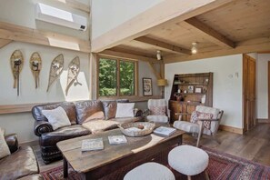 Uma sala de estar acolhedora com um sofá de couro, uma mesa de centro de madeira e uma estante de livros.