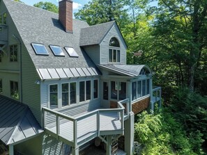 A two-story house with a balcony and a covered porch. - Round Hill Retreat | Epic Stratton Views w Hot Tub (Winhall)