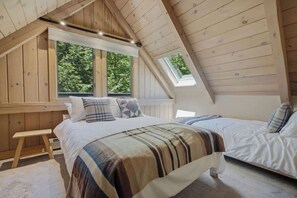 A bedroom with a sloped ceiling, a large window, and a bed with a striped blanket. - Round Hill Retreat | Epic Stratton Views w Hot Tub (Winhall)