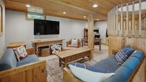 Um interior em madeira com um sofá, uma televisão e uma mesa de madeira.