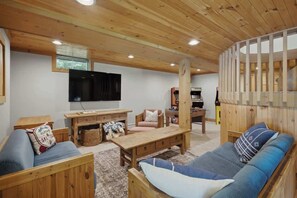 A wooden interior with a sofa, a TV, and a wooden table. - Round Hill Retreat | Epic Stratton Views w Hot Tub (Winhall)
