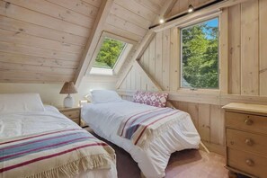 Ein Schlafzimmer mit zwei Betten, einem Fenster und einer Holzbalkendecke.