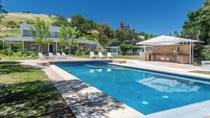 En swimmingpool med en patio, liggestole og grillfaciliteter.
