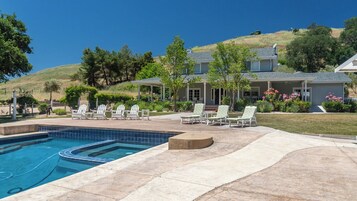 Propiedad residencial con piscina, mobiliario de exterior y un paisaje montañoso de fondo.