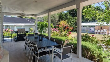 Un patio techado al aire libre con una parrilla, mesa y sillas para comer.