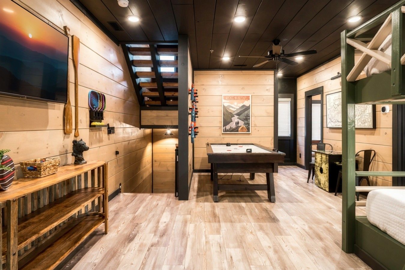 Une pièce chaleureuse avec une table de billard, des murs en bois et un ventilateur au plafond.