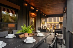 Un espace extérieur aménagé pour les repas, avec une longue table, des chaises et une plante en pot.