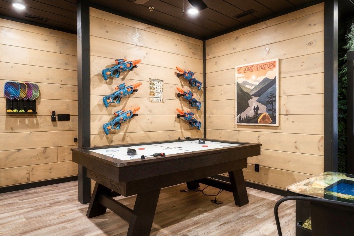 A room with a foosball table, wooden walls, and a poster.