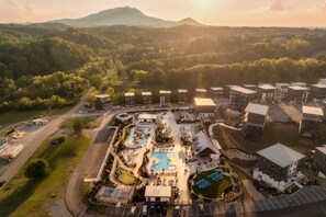 Vue aérienne d’un complexe hôtelier comprenant plusieurs bâtiments, une piscine et un parking.