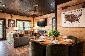 Una habitación acogedora con chimenea, una mesa de comedor dispuesta para cuatro personas y un mapa de Estados Unidos en la pared.