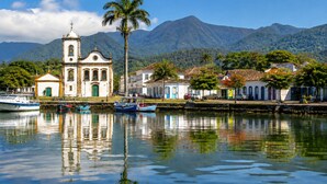 A coastal town with a church, boats, and a mountain backdrop. - Sabará Flats (Paraty)
