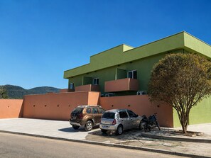 A modern building with a flat roof, a tree in front, and two parked cars.