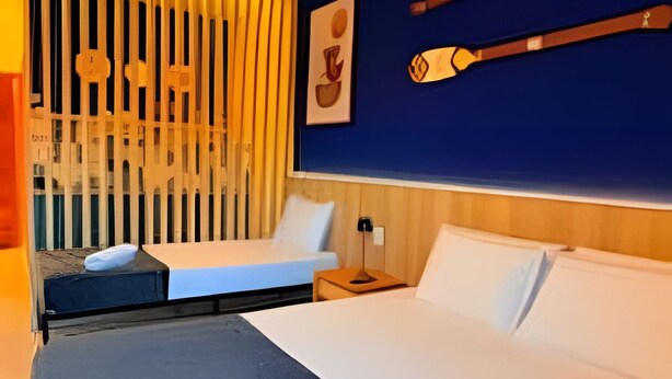 Habitación de hotel con cama, escritorio, silla y ventana con persianas.