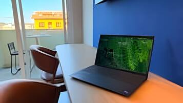 Ein modernes Zimmer mit einem Laptop auf einem Schreibtisch, einem Stuhl und Blick durch ein Fenster.