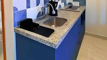 Uma cozinha com parede azul de destaque, bancada de granito, pia e um pequeno objeto decorativo na prateleira.