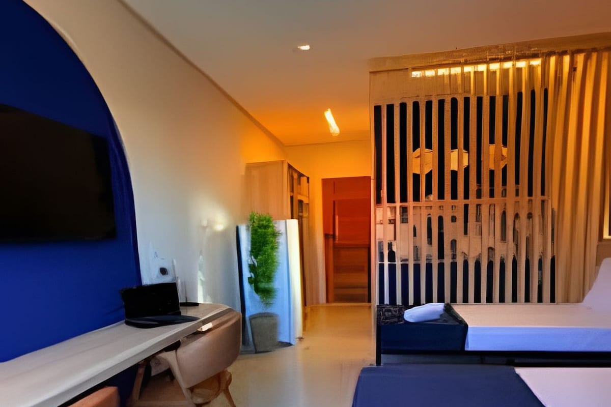 A modern hotel room with a desk, a bed, and a seating area.