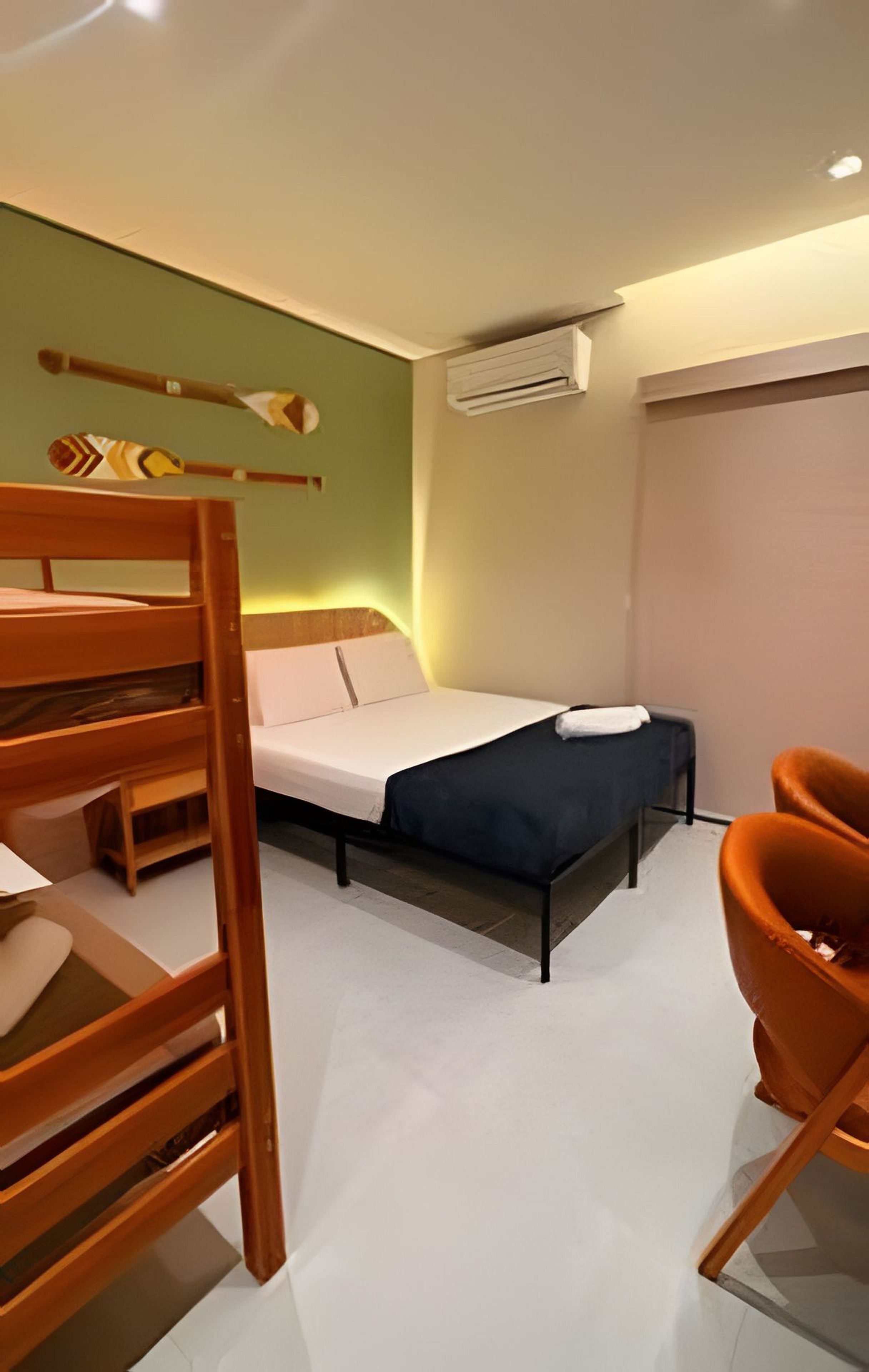 Una habitación con literas, una cama individual, una silla y un equipo de aire acondicionado.