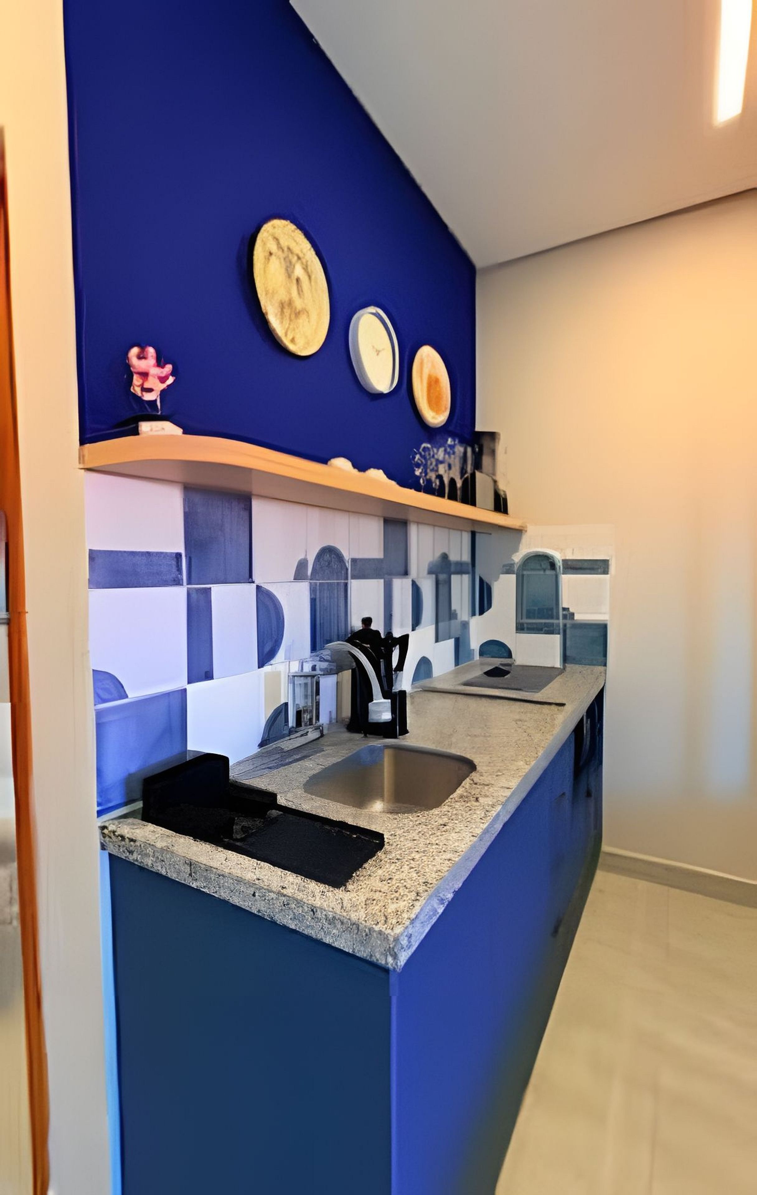 A kitchen with a blue backsplash, a granite countertop, a stainless steel sink, and a small island.
