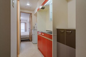 A narrow hallway leading to a room with a bed and a kitchenette area. - LIVIN Osaka Nanbaminami (Naniwa-ward,  Ebisuhonmachi)