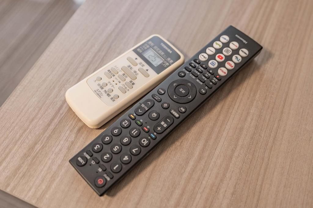 Two remote controls on a wooden surface.