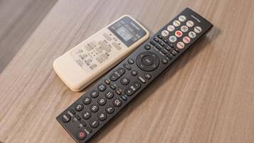 Two remote controls on a wooden surface.
