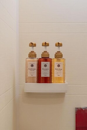 Ein Badezimmerschrank mit drei Kosmetikprodukten, beschriftet mit Conditioner, Shampoo und Duschseife.