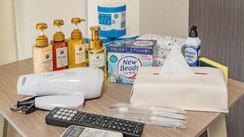 Toiletries, a tissue box, a remote control, and a hairdryer on a hotel room table.