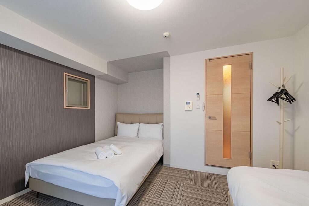 A hotel room with a single bed, a wooden wardrobe, a mirror, and a coat rack.