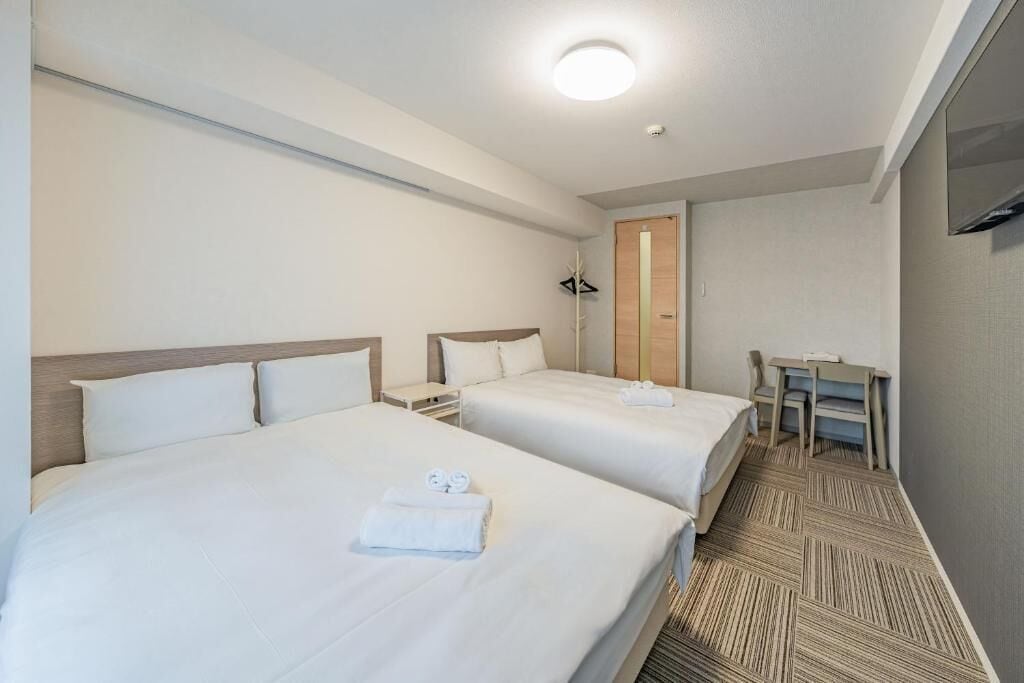 A hotel room with two beds, a desk, and a chair.