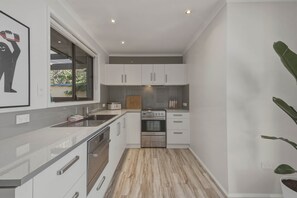 Eine moderne Küche mit weißen Schränken, Edelstahlgeräten und einer Holz Arbeitsplatte.