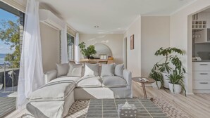 Uma sala de estar moderna com um sofá modular, uma mesinha redonda e várias plantas em vasos.