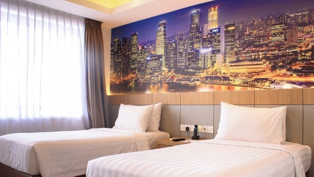 Habitación de hotel con dos camas, vistas a la ciudad y un teléfono en la mesita de noche.
