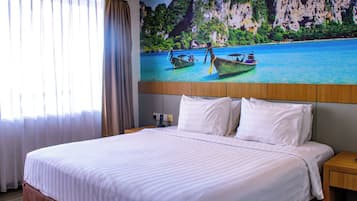 Quarto de hotel com uma cama grande, cabeceira com pintura de barcos na água, mesa de cabeceira e janela com cortinas.