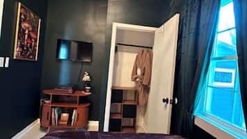 A bedroom with a bed, a desk, a chair, a lamp, a wardrobe, and a window with curtains.