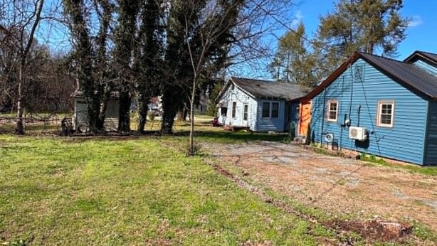 A rural property with a blue house, a small white building, and a grassy area with trees. - FOX DEN COTTAGE (Cleveland)