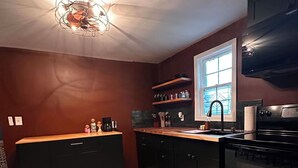 A compact kitchen with dark cabinetry, a central island, and a window above the sink. - FOX DEN COTTAGE (Cleveland)