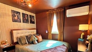 A bedroom with a bed, a nightstand, a dresser, a window with curtains, and a wall-mounted air conditioner. - FOX DEN COTTAGE (Cleveland)