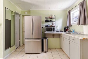 A compact kitchen with a stainless steel refrigerator, a microwave, and a sink. - Quiet Studio with Sunny Private Yard (Wilton Manors)