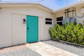 A building with a turquoise door, a small window, and a hedge. - Quiet Studio with Sunny Private Yard (Wilton Manors)