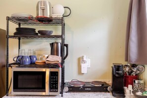 Una kitchenette equipada con microondas, hervidor y cafetera.