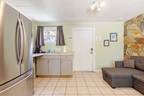 A compact kitchen with a refrigerator, a sink, and a stone wall. - Quiet Studio with Sunny Private Yard (Wilton Manors)