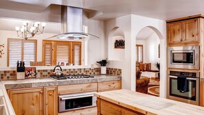 Cocina moderna con armarios de madera, estufa a gas, microondas y una isla grande con hervidor.