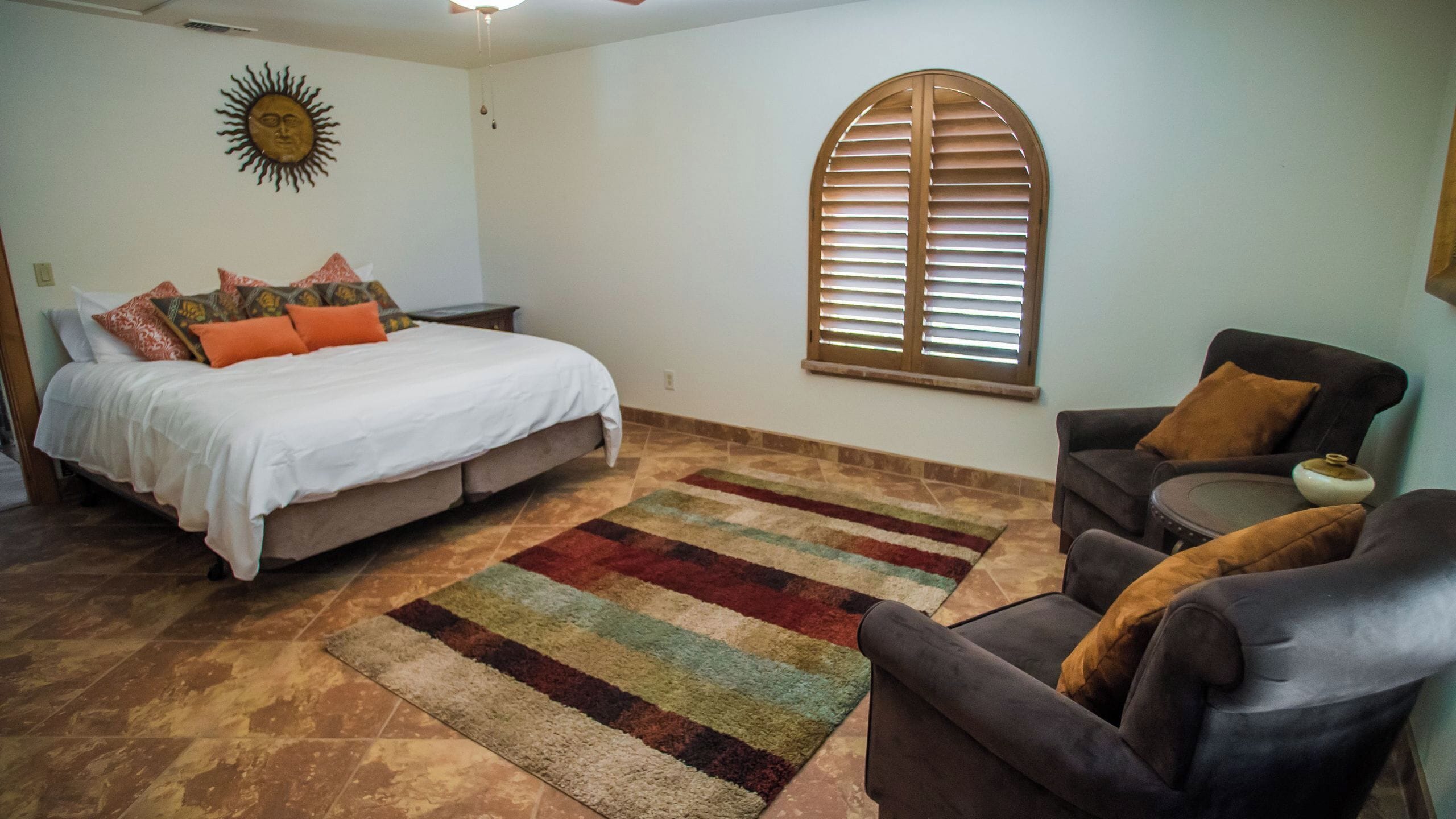 Un dormitorio con cama, sofá, ventana con contraventanas y un adorno en la pared.