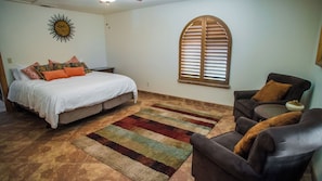 A bedroom with a bed, a sofa, a window with shutters, and a decorative wall piece. - Hacienda in Solitude Vineyard by Avantstay Vineyard Views + Patio Paso Robles (Paso Robles)