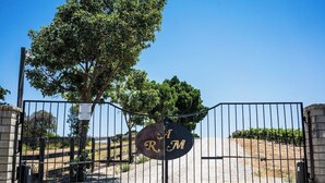 Una entrada con puerta de acceso y un letrero que dice 'R M', con un árbol al fondo.